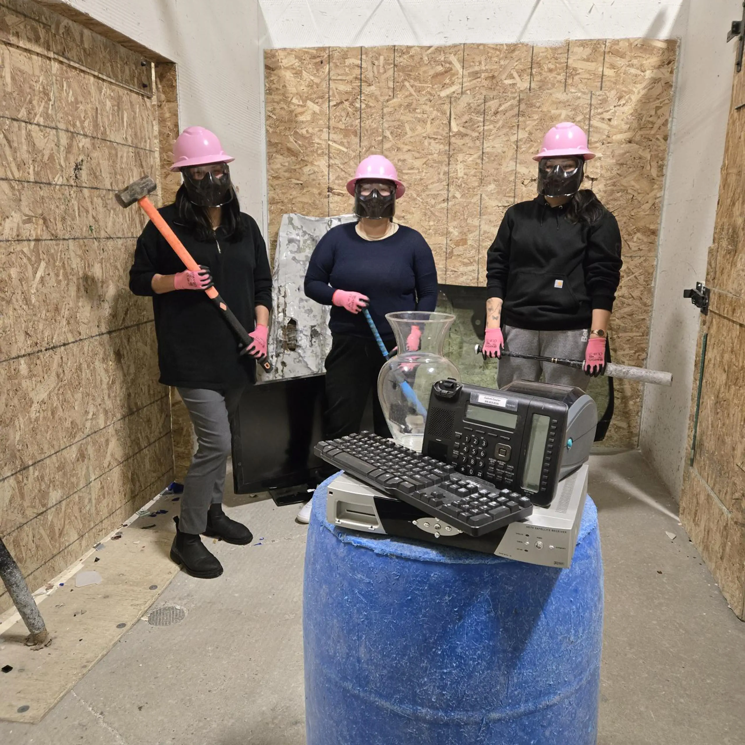 Group of people wearing protective gear holding hammers and bats ready to smash a pile of electronics Group of people wearing protective gear holding hammers and bats ready to smash a pile of electronics